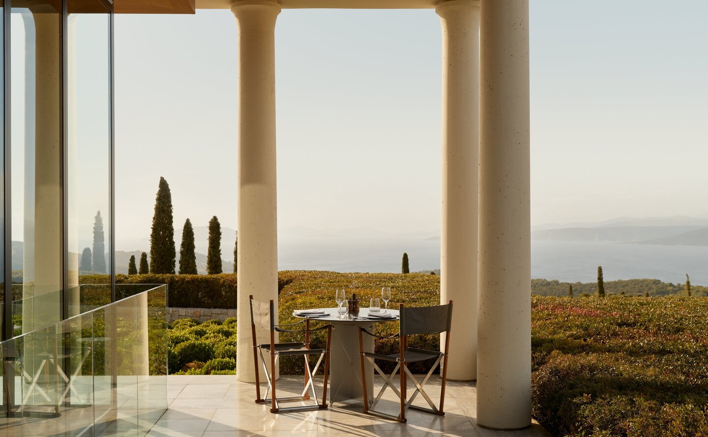 Main restaurant at Amanzoe overlooking the Peloponnese coastline at dusk.