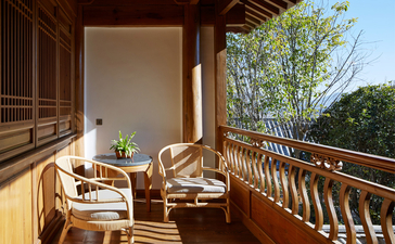 Wooden deck at Amandayan with dining chairs overlooking verdant hillside views.