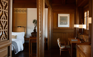 Warm wooden interior at Amandayan with principal bedroom visible through open doorway, leather chair, and framed artwork.