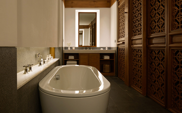 Sunlit bathroom at Amandayan with round soaking tub and carved wooden cabinetry.