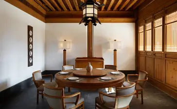 Wooden-beamed interior at Amandayan with round dining table, chairs, and pendant lighting.