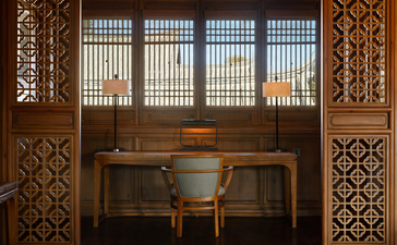 大研安缦度假村内，木制屏风框架的书房，配以传统雕花装饰和窗户采光。