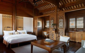 大研安缦度假村宽敞的卧室，配有传统木质框架、白色床上用品和简约家具。