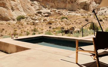 Amangiri's plunge pool overlooking desert landscape with lounge chair in foreground.