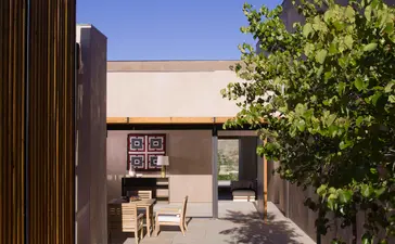 Amangiri courtyard with wooden screen wall, modernist building, and climbing vine vegetation.