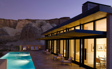 アマンギリ・リゾートの夜景。砂岩の崖を背景に、明かりが灯る建築と輝くプール。