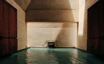 Plunge pool at Amangiri with stone walls and dark wooden doors at either end.