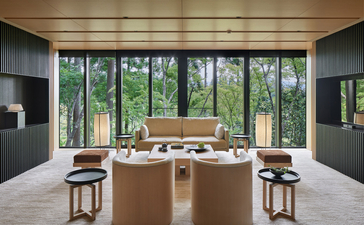 Aman Kyoto resort dining room with wooden table, floor-to-ceiling windows overlooking forest, and minimalist décor.