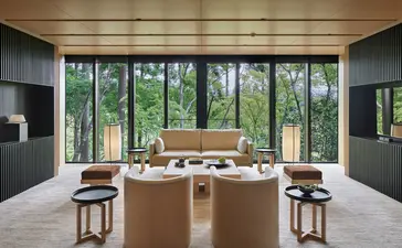 安缦京都度假村的餐饮空间，木制长餐桌面向森林景观，大窗户自然采光。