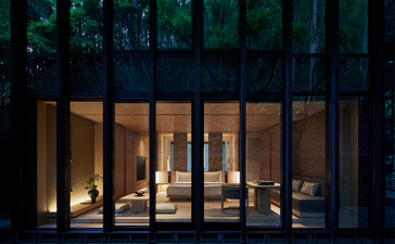 Aman Kyoto resort, evening view through illuminated glass doors and wooden frames.