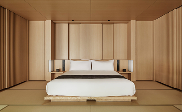 Principal bedroom with canopied bed at Aman Kyoto resort, featuring warm wood panelling and minimalist design.