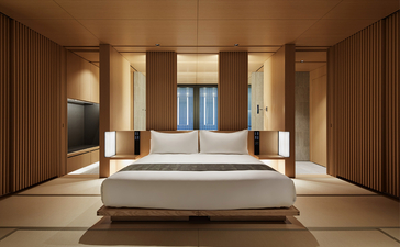 Principal bedroom at Aman Kyoto with wooden platform bed, soft lighting, and symmetrical wardrobe storage.