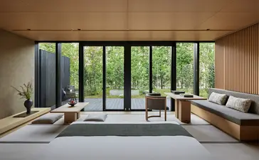 安缦京都度假村的宽敞室内空间，落地窗俯瞰绿色花园景观。