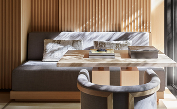 Principal bedroom at Aman Kyoto with layered bedding, warm wood panelling, and a circular side table.