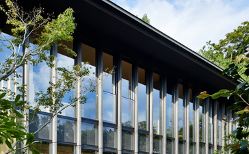 Aman Kyoto's modern pavilion with floor-to-ceiling columns framed by lush greenery.