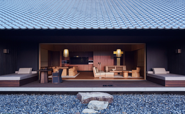 Amanemu resort pavilion with wooden interior and open design overlooking a blue courtyard at dusk.
