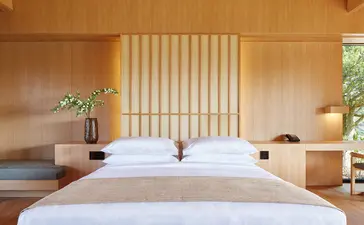 Deux lits jumeaux dans une chambre aux teintes chaudes avec écran en bois ajouré, Amanemu.