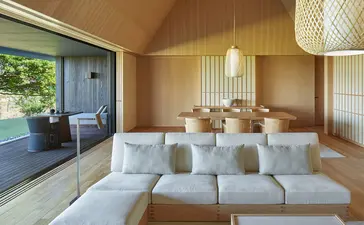 Spacious principal bedroom with neutral furnishings and wooden ceiling at Amanemu resort.