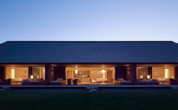 Amanemu's modernist pavilion glows warmly at dusk beneath a clear sky.