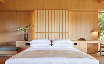 Two beds in a minimalist principal bedroom at Amanemu with wooden walls and soft natural light.