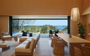 Sala d'attesa con vista sul mare presso il resort Amanemu, con arredi minimalisti e finestre panoramiche.