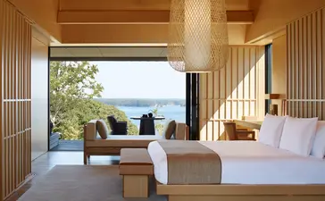 Principal bedroom with open terrace overlooking water at Amanemu resort.
