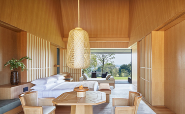 Amanemu resort spa treatment room with wooden interiors, massage table, and garden views through open doors.