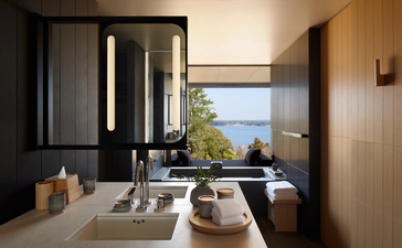 Spaziosa sala da bagno con pareti in legno chiaro, finestra con vista sul mare e arredi minimalisti presso il resort Amanemu.