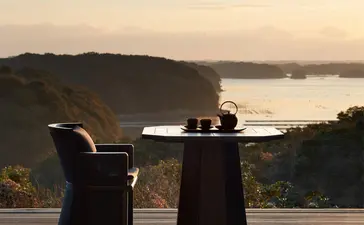 安缦伊沐度假村露台上，两个人举起酒杯，俯瞰宁静的湖景。