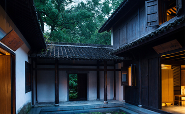 Amanfayun courtyard at dusk with traditional architecture and softly lit interiors.