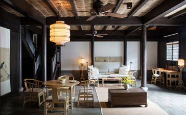 Amanfayun lounge with dark wooden beams, pendant lighting, and views across the landscape through large windows.