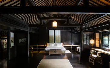 Amanfayun spa treatment room with dark timber ceiling, sunken bath, and warm lantern lighting.