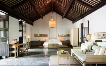 Amanfayun villa interior with high ceiling, wooden beams, neutral furnishings and natural light.