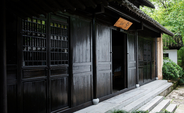 Black wooden entrance pavilion at Amanfayun nestled amongst verdant foliage.