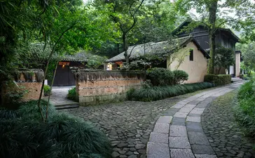 Stone pathway winding through lush greenery towards traditional architecture at Amanfayun.