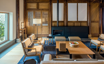 Amanyangyun lounge with wooden screens, blue seating, and natural light from floor-to-ceiling windows.