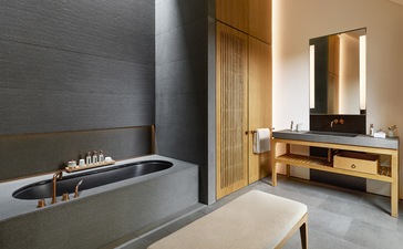 养云安缦度假村的浴室，采用深色瓷砖浴缸和木质盥洗台，简洁现代的设计风格。