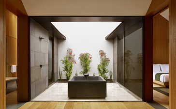 养云安缦度假村的入口庭院，中央置有绿色植物，两侧为木质门框。