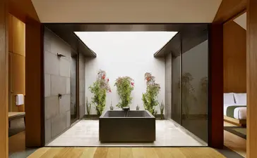 养云安缦度假村的入口庭院，中央置有绿色植物，两侧为木质门框。