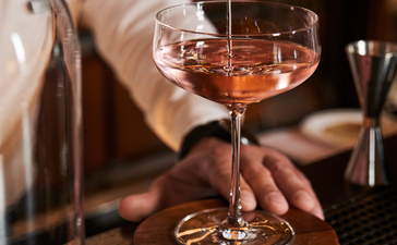 Bartender pouring a cocktail into a coupe glass at Aman Venice's bar.
