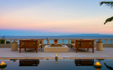 安缦丘澜度假村套房露台，黄昏时分俯瞰海景，配有木制座椅和照明灯。