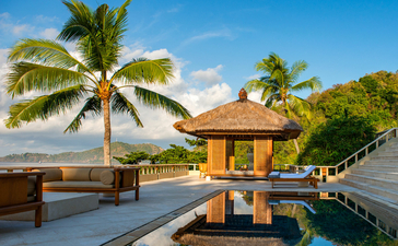 安缦丘澜度假村的套房露台，配有无边泳池、棕榈树和巴厘岛海景。