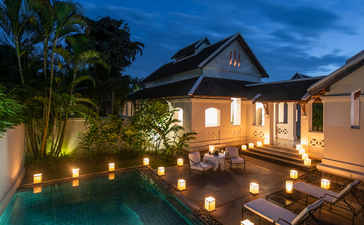 Pool Suite at Amantaka, Laos, illuminated at dusk with candlelit courtyard.