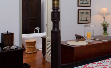 Principal bedroom at Amangalla with dark wood furniture and desk workspace, Sri Lanka.