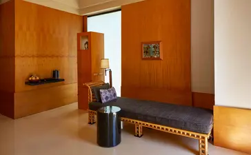 Borobudur Suite at Amanjiwo with wooden walls, bench seating, and doorway to bathing area.