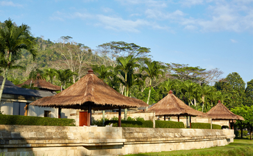 Borobudur Suite pavilion with thatched roof at Amanjiwo resort, Indonesia, surrounded by tropical gardens.
