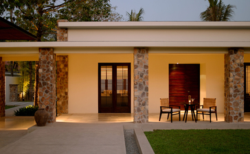 Contemporary Suite exterior at Amansara, Cambodia, with stone walls and yellow façade at dusk.