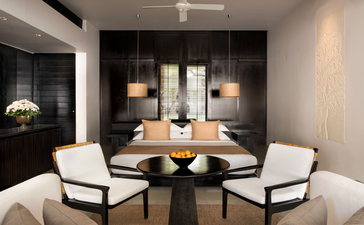 Contemporary Suite at Amansara with wooden dining table, white chairs, and candlelit ambiance.