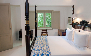 Principal bedroom at Amangalla with four-poster bed and garden views through open windows.