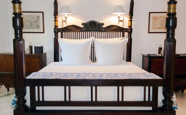 Principal bedroom at Amangalla with four-poster bed and dark wood furnishings.